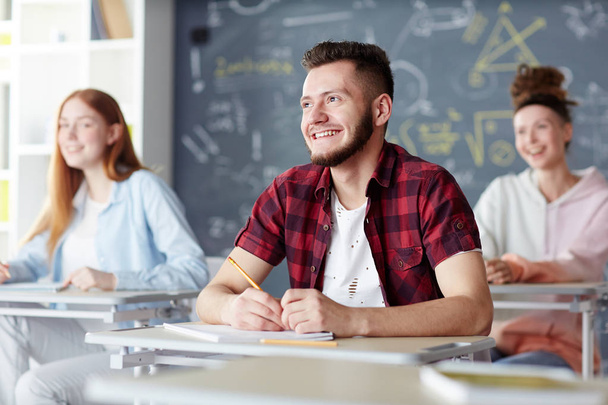 High-school learner looking at teacher with smile while listening to explanation at lesson - Photo, Image