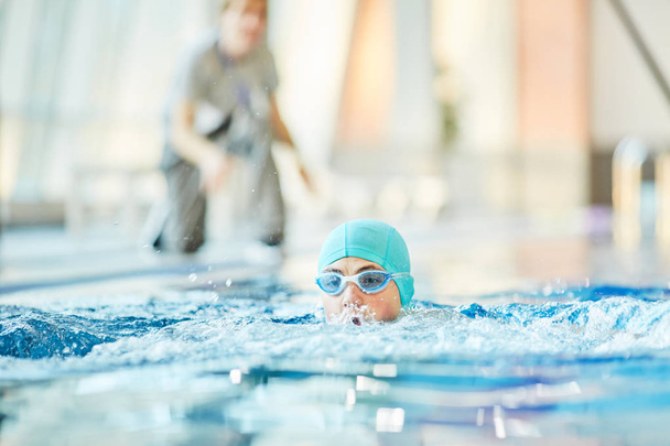 Nuori poika suojalaseissa ja uimalakki harjoitellaan uinti ohjeita hänen kouluttaja
 - Valokuva, kuva