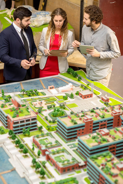 Três jovens designers urbanos discutindo detalhes do novo distrito da cidade
 - Foto, Imagem