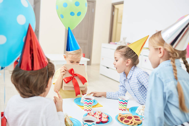 Giftbox açma ve doğum günü hediyesi içinde arkadaşları ile kutlama sırasında bakarak küçük çocuk - Fotoğraf, Görsel