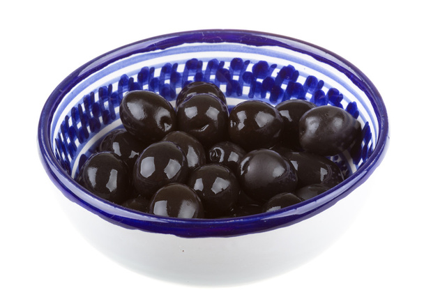Оливки черные поливаются оливковым маслом в чаше, изолированной на белом
 - Фото, изображение