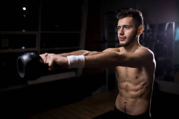 Hombre con brazos estirados levantando pesas durante el entrenamiento en el gimnasio
 - Foto, Imagen