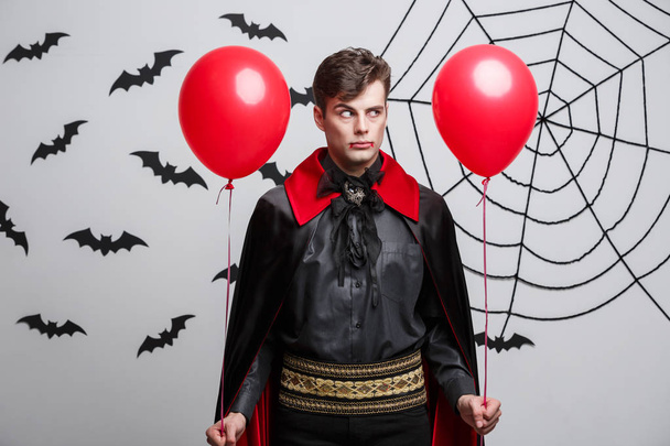 Retrato de guapo caucásico en traje de Halloween vampiro con colorido globo
. - Foto, Imagen