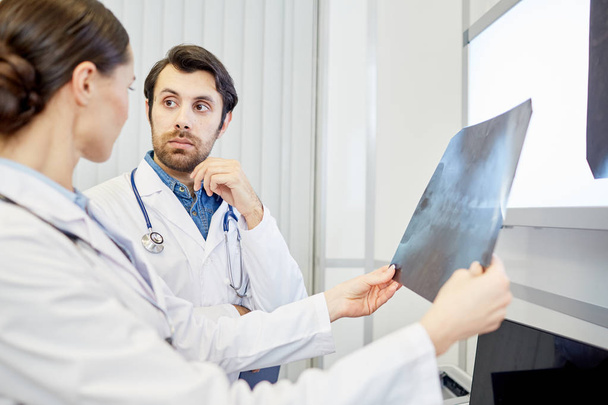 Serious radiologist listening to his colleague during discussion of patient results - Foto, Imagem
