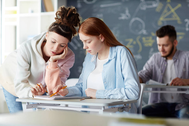 zwei moderne Studenten diskutieren im Klassenzimmer vor dem Unterricht über Vorlesungsnotizen - Foto, Bild