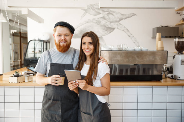 Концепція кавового бізнесу - щаслива молода пара власників бізнесу маленької кав'ярні, що працює і планується на планшеті
. - Фото, зображення
