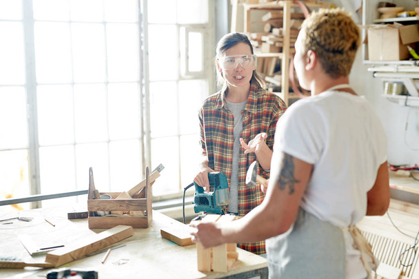 Duas carpinteiras conversando ou consultando durante o trabalho
 - Foto, Imagem
