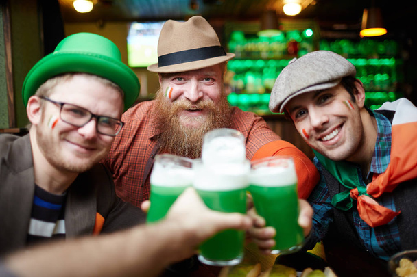 Heureux amis griller avec des verres de bière moussante tout en se rassemblant dans le pub
 - Photo, image