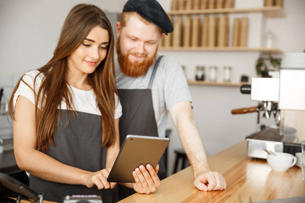 Kávé üzleti Concept - elégedett és mosoly tulajdonosok pár végignéz tabletta online megrendelés a modern kávézó - Fotó, kép