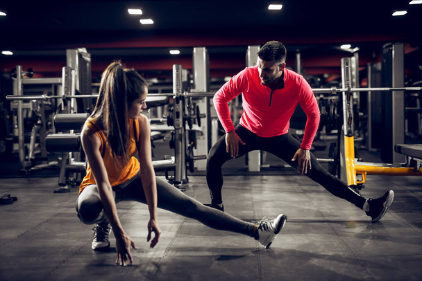 attraente giovane donna in abbigliamento sportivo facendo gambe stretching con personal trainer in palestra
 - Foto, immagini