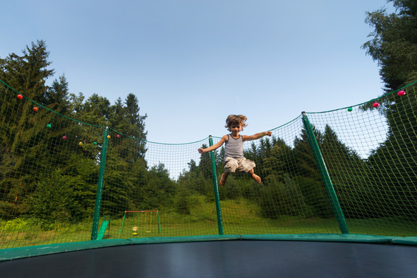 mignon garçon aime sauter et rebondir sur trampoline à l'extérieur
. - Photo, image