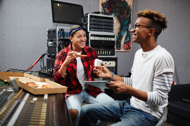 Deux opérateurs du son prenant une pizza et un café dans leur studio de disques à la pause déjeuner
 - Photo, image