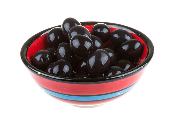 Aceitunas negras regadas con aceite de oliva en un bol aislado sobre un fondo blanco
 - Foto, Imagen