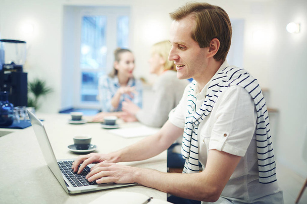 Молодий мобільний чоловік друкує на клавіатурі ноутбука і читає інформацію в Інтернеті
 - Фото, зображення