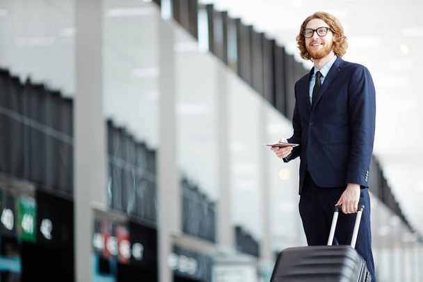 Exitoso hombre de negocios con equipaje, pasaporte y billete que va a la plataforma de salida
 - Foto, Imagen