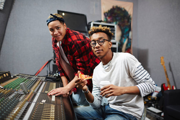 Uomo con pizza e bevande e il suo collega che trascorre la giornata lavorativa in studio di registrazione del suono
 - Foto, immagini