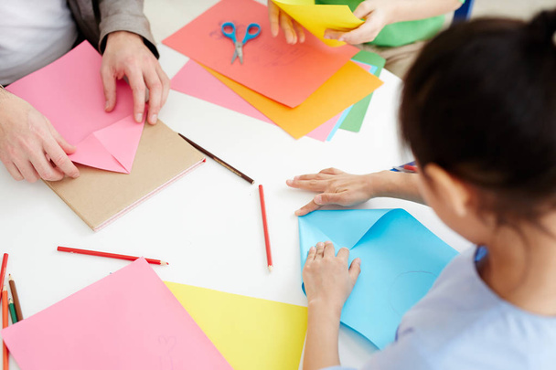 Leerlingen van de middelbare school met behulp van roze en blauwe papier terwijl het maken van origami - Foto, afbeelding