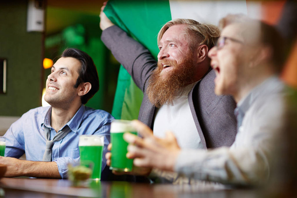 国立アイルランドのフットボールのファンはフラグのパブでビールを一杯放送テレビを見ています。 - 写真・画像