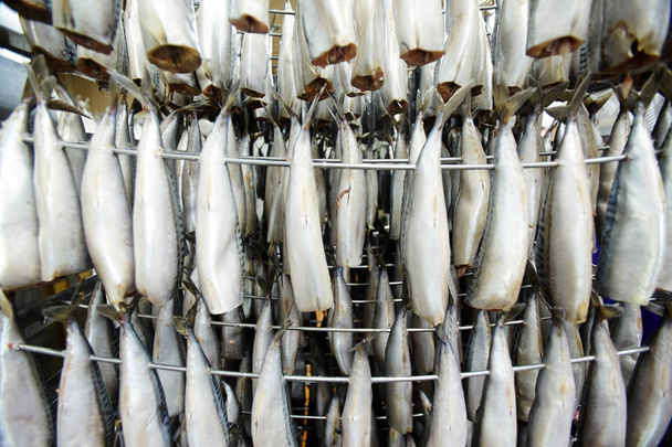 Сирі макрелі висять на дротах перед переробкою диму на рибному заводі
 - Фото, зображення