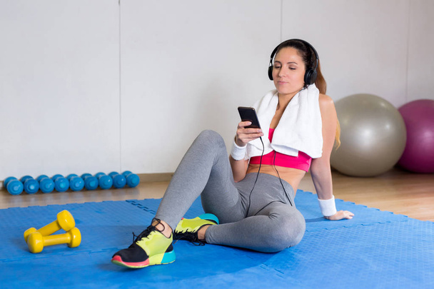 Молодая современная женщина в активной одежде слушает музыку после спортивных тренировок
 - Фото, изображение