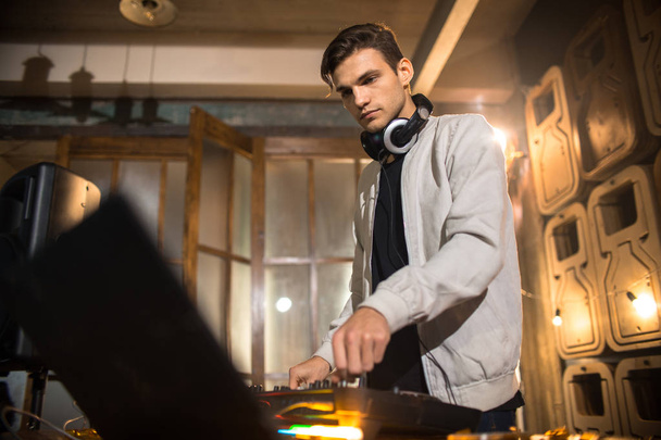 Side View muotokuva trendikäs nuori DJ soittaa musiikkia mikseri ja katsomalla kannettava näyttö yökerho osapuoli, kopioi tilaa
 - Valokuva, kuva