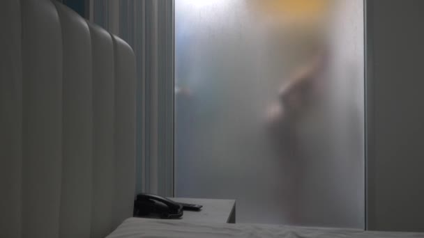 Woman behind blurry glass. Girl preparing take shower. Woman in bathroom. a man watches as a woman takes a shower through a glass wall in the shower. 4k - Filmati, video