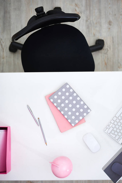 Interior do escritório moderno do trabalhador de colarinho branco feminino: mesa de madeira com artigos de papelaria rosa e computador moderno, cadeira giratória, diretamente acima vista
 - Foto, Imagem