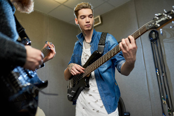 Jeune musicien rockstar talentueux pratiquant la guitare avec professeur en studio d'enregistrement tout en apprenant une nouvelle chanson
 - Photo, image