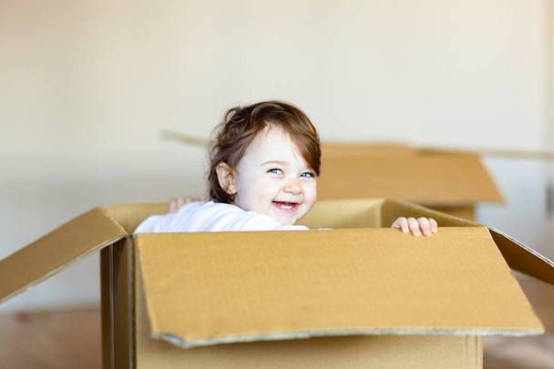 Toddler baby girl sitting inside brown cardboard box. - Photo, Image