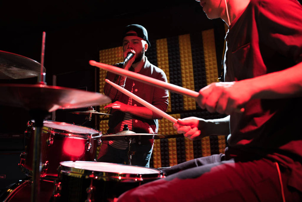 Retrato del cantante de hip-hop actuando con su banda en el estudio de grabación, baterista en escena de primer plano iluminado por la luz roja
 - Foto, imagen