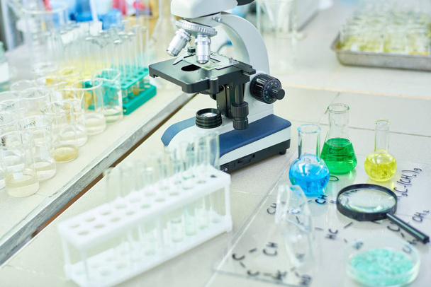 Angle élevé de divers équipements scientifiques sur table de travail dans un laboratoire de recherche, microscope moderne entouré de tubes à essai et de verrerie
 - Photo, image