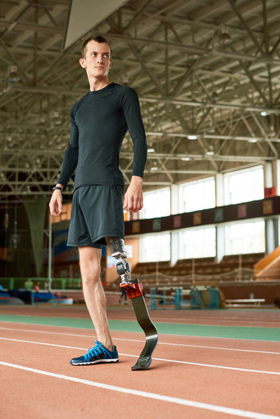 Портрет молодого спортсмена-амбулатора, який стоїть на біговій доріжці перед тренуванням на сучасному критому стадіоні
 - Фото, зображення