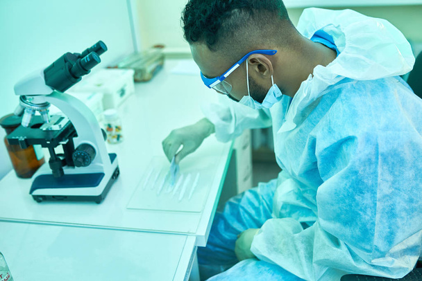 Retrato de alto ângulo do jovem cientista do Oriente Médio que trabalha com substâncias em laboratório fazendo pesquisa médica
 - Foto, Imagem