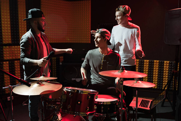 Portret van moderne hip-hop band repeteren in de opnamestudio verlicht door rood licht terwijl het maken van nieuwe album - Foto, afbeelding