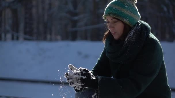 Slow-mo záběry. Krásná mladá dívka dělat sněhové koule v lese - Záběry, video