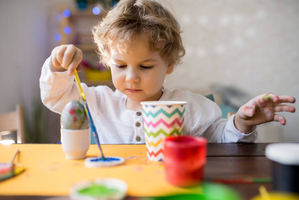 Retrato de adorable niño pintando huevos de Pascua haciendo decoraciones hechas a mano en casa
 - Foto, imagen