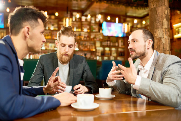 Group of talented managers gathered together in modern cafe, drinking fragrant coffee and sharing ideas with each other concerning start-up project - 写真・画像