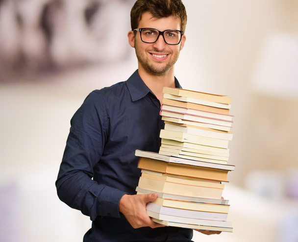 Молодий щасливий чоловік тримає купу книг
 - Фото, зображення