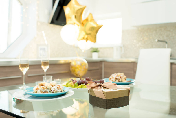 Imagem de fundo da mesa de jantar servido para data romântica no dia dos namorados no quarto decorado com balões, foco na caixa em forma de coração de chocolates
 - Foto, Imagem