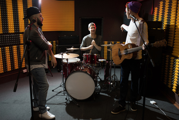 Yhtye nuoria muusikoita keskustelemassa esiintyessään dim-äänitysstudiossa tekemässä uutta albumia
 - Valokuva, kuva