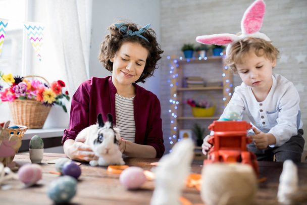Scena di vita domestica: madre e figlio celebrano la Pasqua a casa e giocano con simpatico coniglietto domestico
 - Foto, immagini