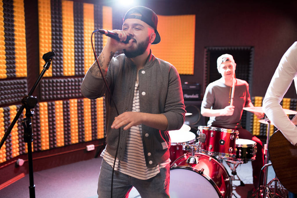 Portrait of modern hip-hop singer performing with his band in recording studio while making new album, copy space - Photo, Image
