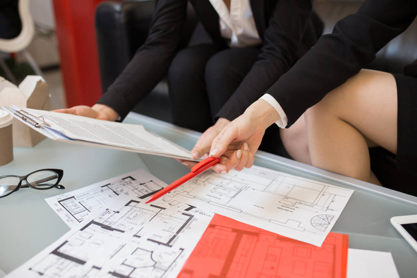 Close up de pessoas discutindo documentos e planos de chão sobre mesa de café na agência imobiliária
 - Foto, Imagem
