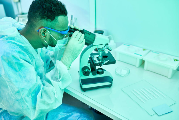 Retrato de vista lateral de un joven científico de Oriente Medio que usa microscopio mientras trabaja en laboratorio haciendo investigación médica
 - Foto, Imagen