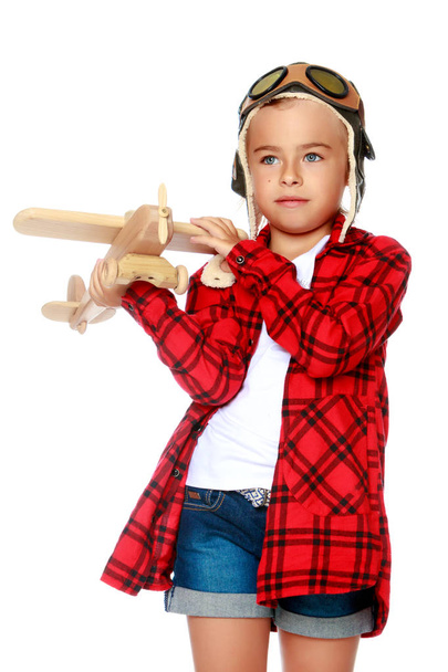 Klein meisje met een houten vliegtuig in haar hand. - Foto, afbeelding
