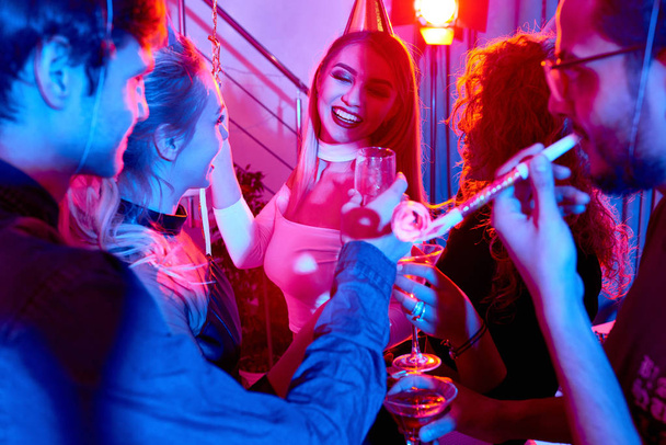 Mooie vrouw geniet van aandacht op verjaardag party in discotheek dansen, verlicht door blauw licht - Foto, afbeelding