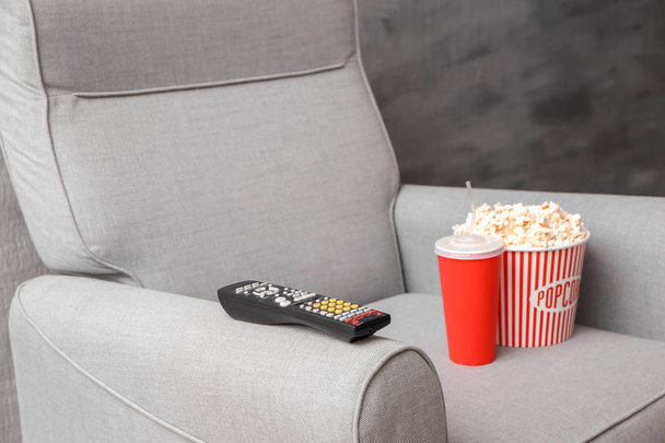 Comfortable armchair with TV remote control and snack indoors. Home cinema - Foto, Bild