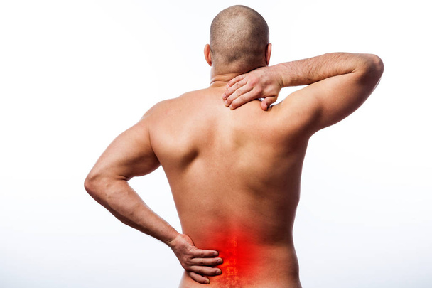 Pain in the spine.  Young bald man sports physique holds a sick back on a white isolated background. Fracture of spine - Photo, Image