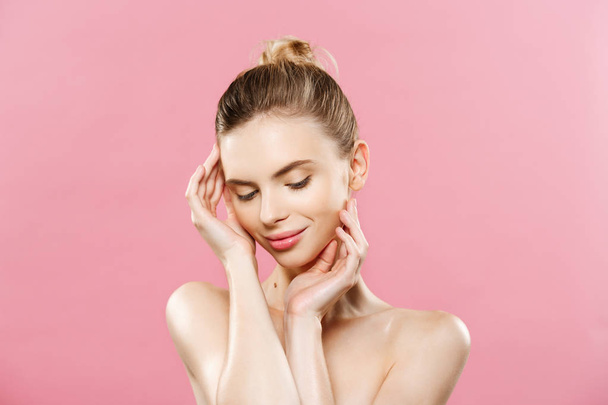 Beauty Spa Concept - Caucasian Woman with perfect face skin Portrait. Beautiful Brunette Spa Girl showing empty copy space. Isolated on pink studio background. Proposing a product. - Photo, Image