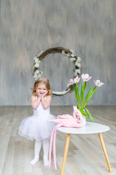 Beautiful little girl model view in a luxury white dress and tulips - Foto, afbeelding
